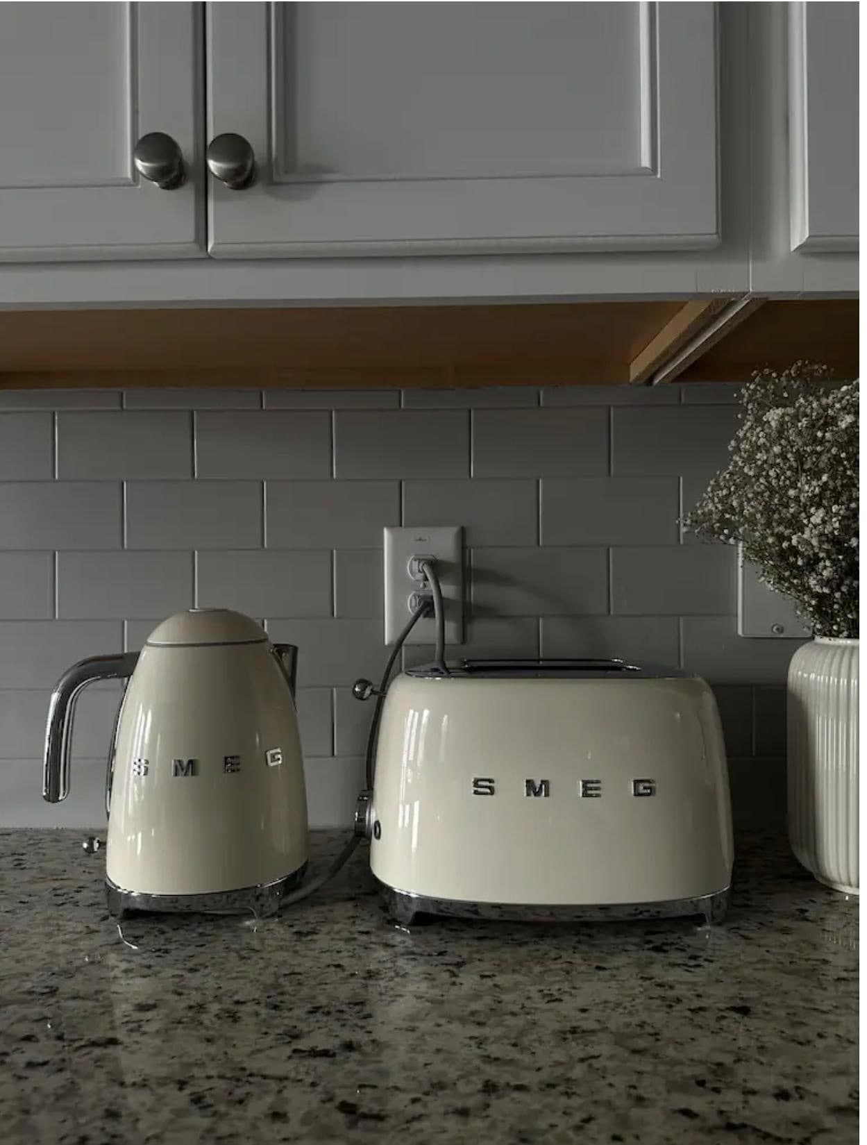 Cream kettle and toaster on a granite counter under gray cabinets
